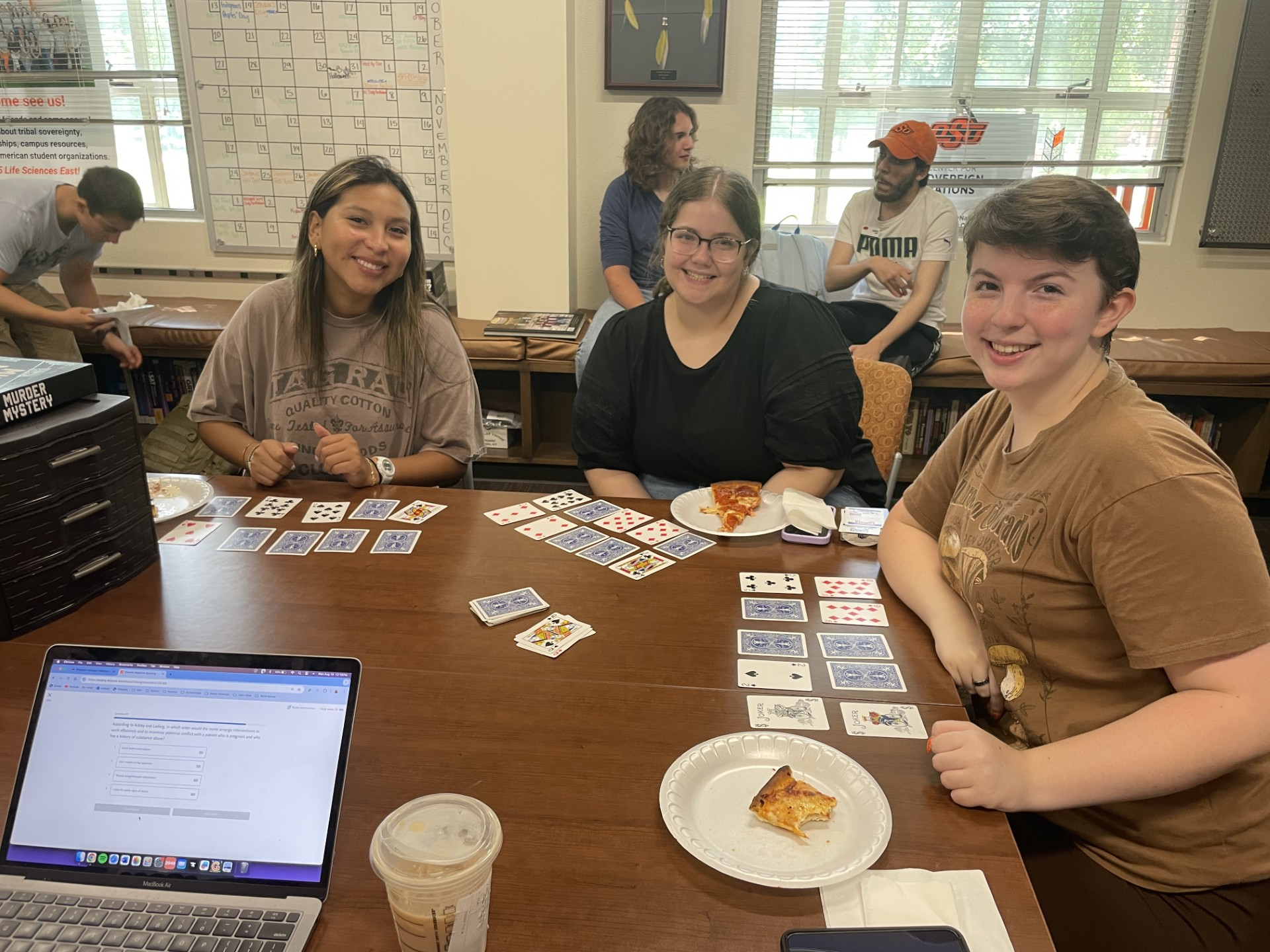 Three people smiling at the camera while playing a card game.png